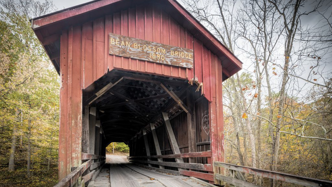 Red covered bridge with sign reading "Bean Blossom Bridge 1880"