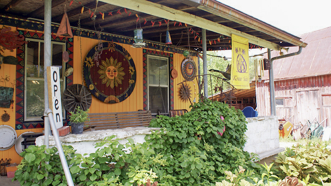 Exterior of a bright yellow building with plans below the porch and an Open sign