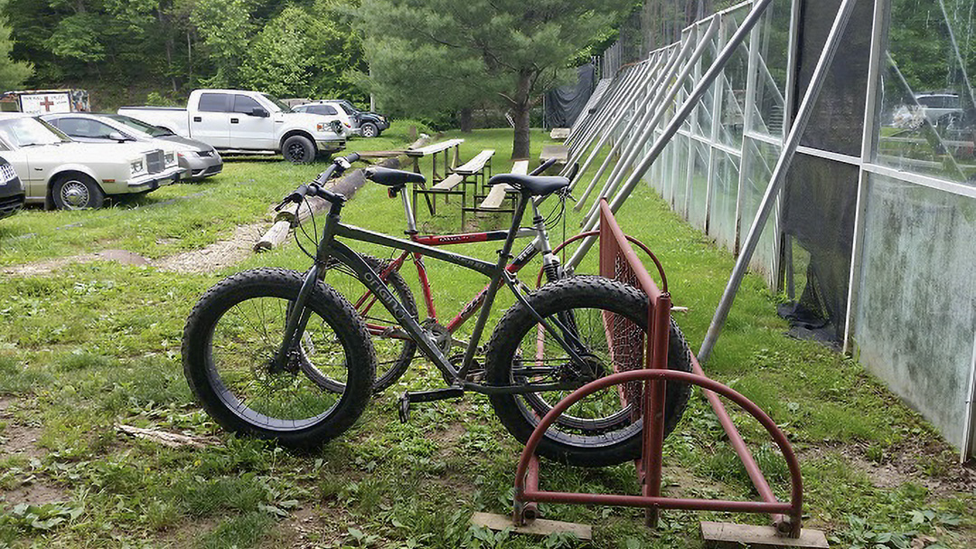 Fat Tire bike is parked at a bike rack with cars in the background