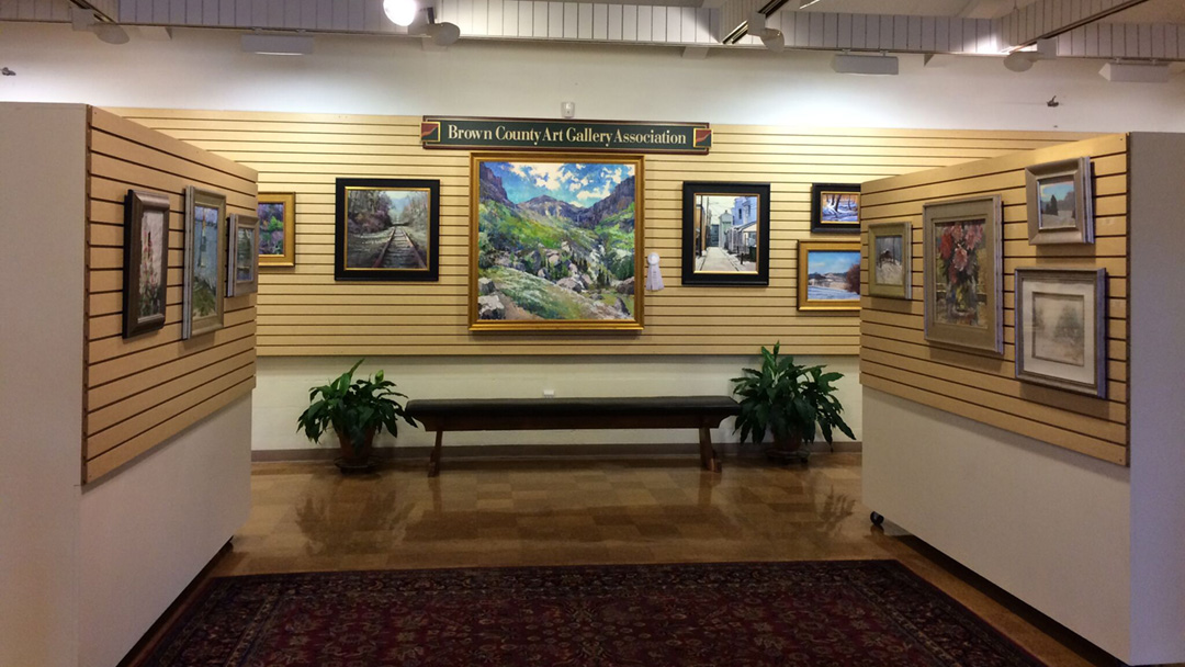 Interior of the Brown County Art Gallery with paintings on the walls and a bench