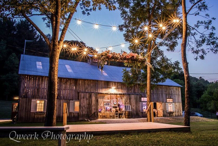 Evening exterior of an old barn with lights hanging over a wood-plank dance floor