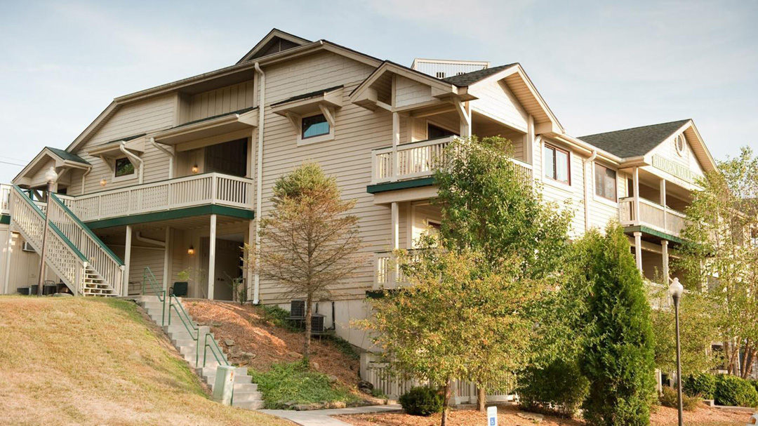 Exterior of the Hidden Valley Inn - a large structure built on a hill with outdoor staircase, balconies and landscaping