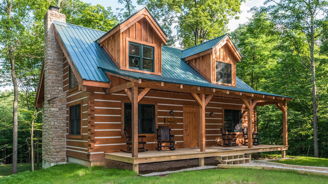 Log Cabin with a large porch and stone chimney