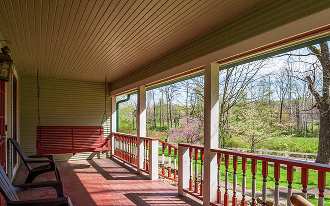 Exterior of a large porch on a farm house looking out onto the yard