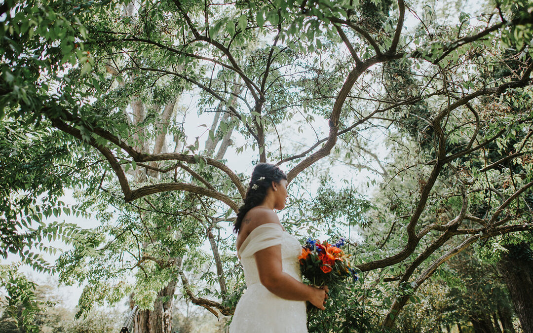 Bride holding a bouquet of flowers beneath a canopy of trees