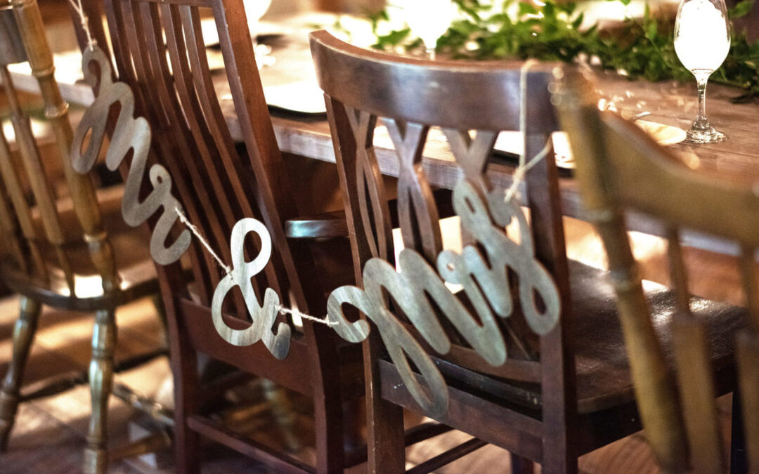 Rustic wooden chairs with letters spelling "Mr & Mrs" hanging off the backs of two chairs