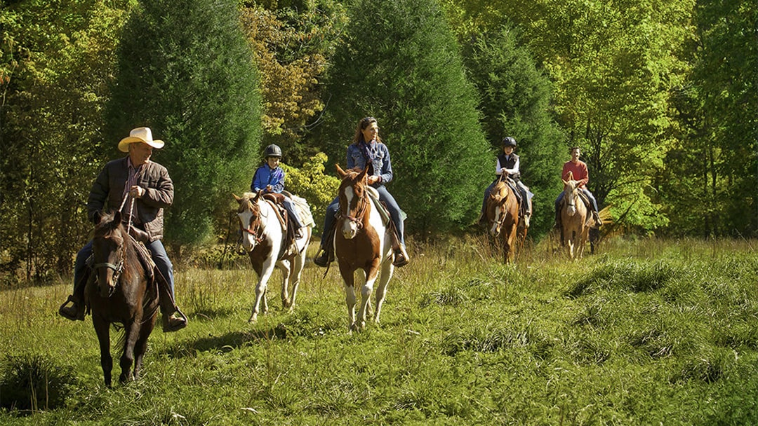 Family riding horseback with a guide leading them