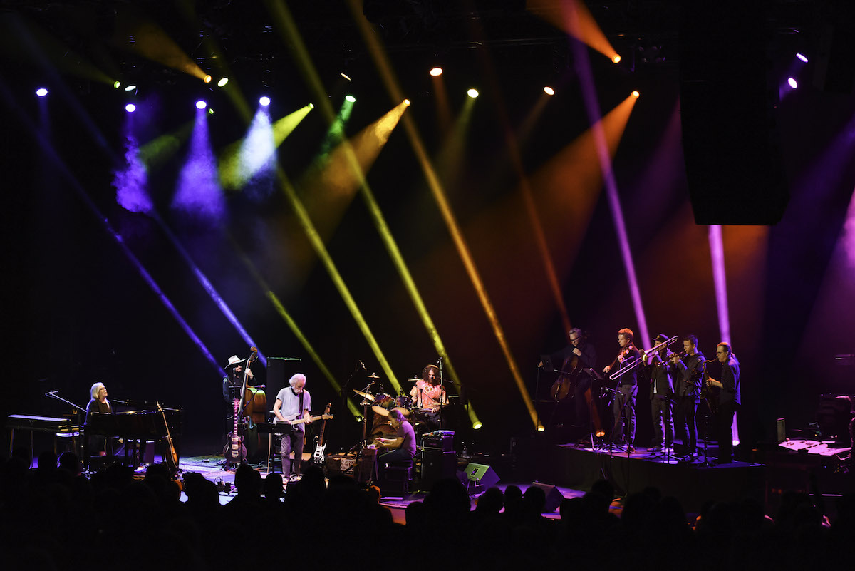 Evening concert photo of a brand playing on a large stage with colorful spotlights. 