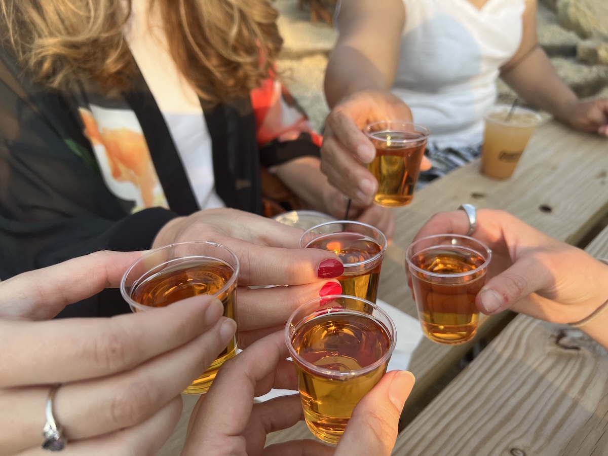 Hands from several people holding shot glasses, getting ready to cheers each other. 