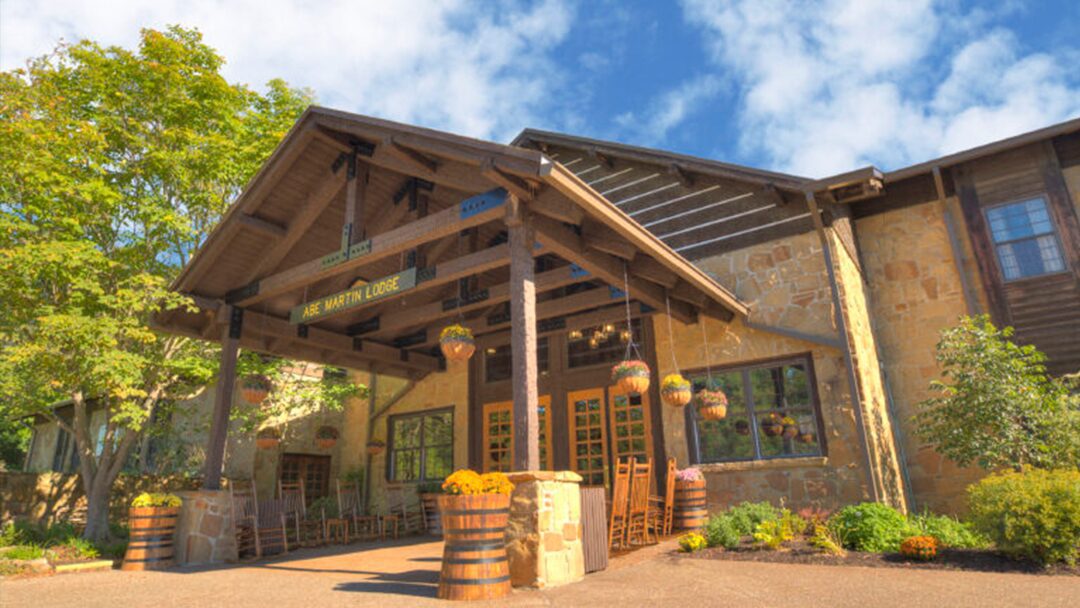 Standing paddlers on water surrounded by trees.