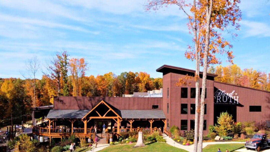 Standing paddlers on water surrounded by trees.